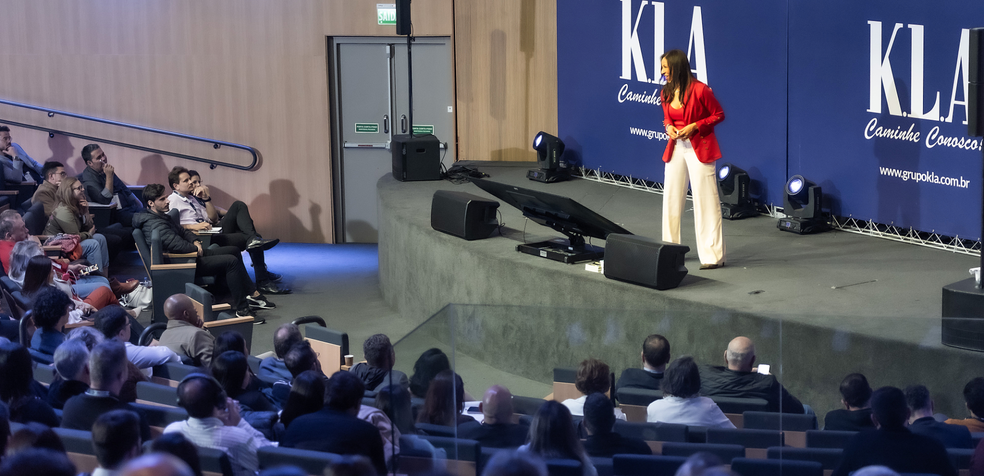 Débora Santos palestrando no palco para uma plateia lotada